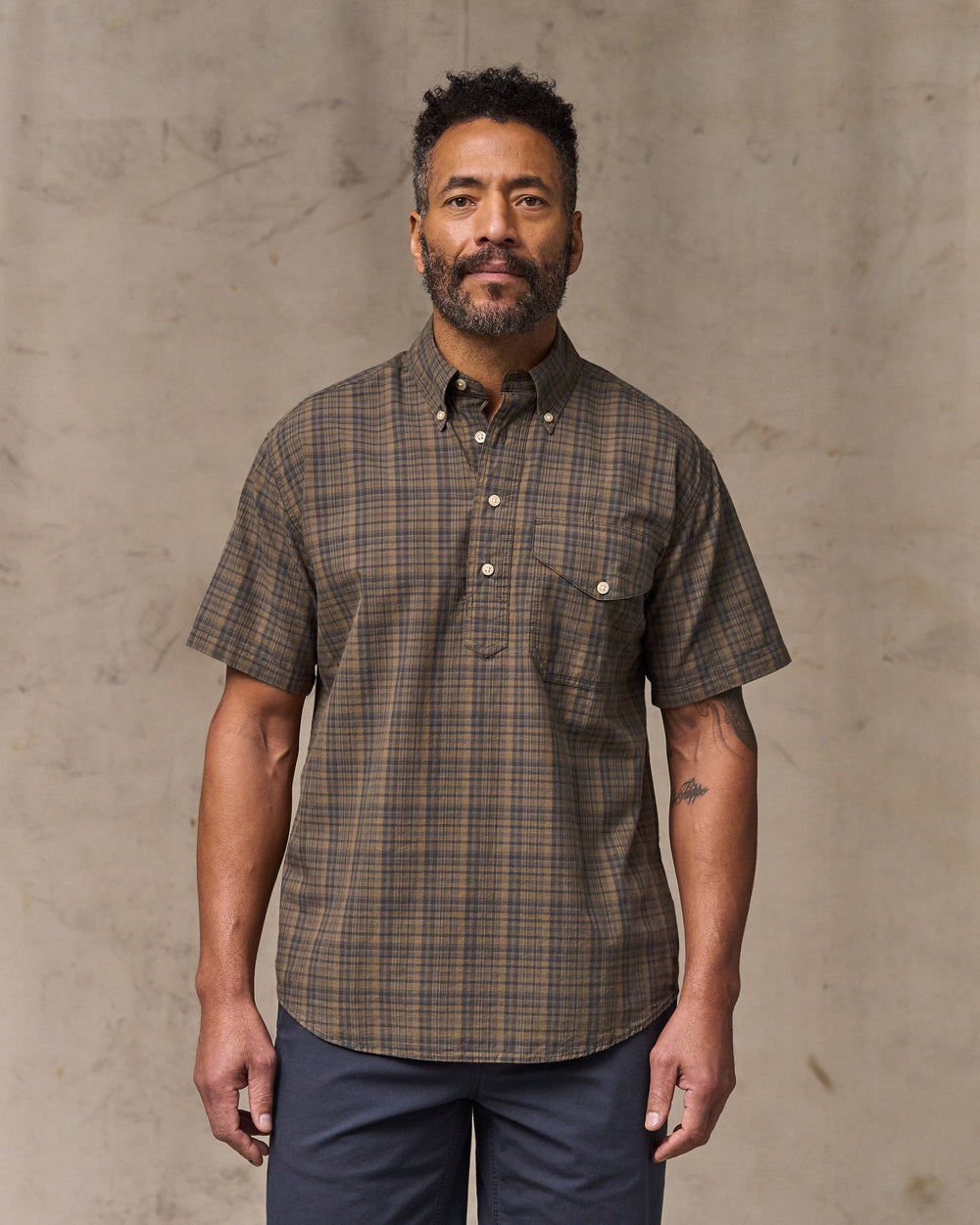 image of a model wearing Filson's Short Sleeve Madras Popover Shirt - Brown / Olive Plaid
