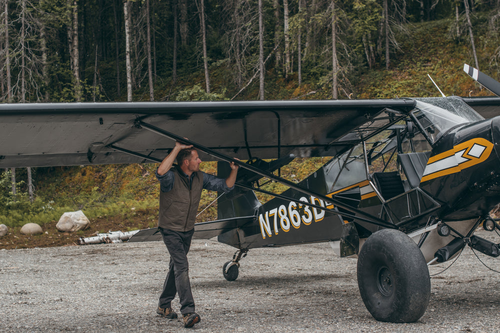 Pilot rolling a bush plane on a gravel path while wearing Filson Bremerton Work Pants