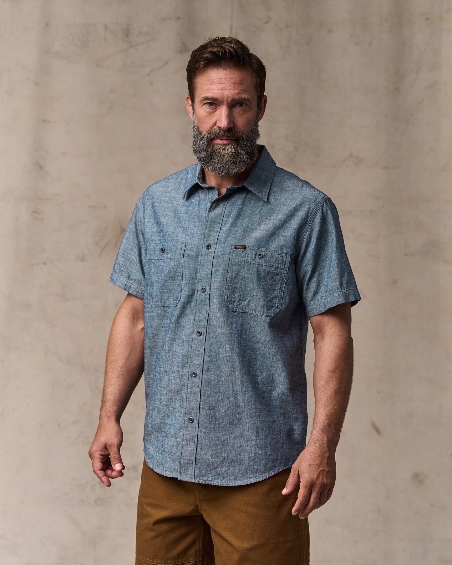image of a model wearing Filson's Short-sleeve Embroidered Chambray Shirt - Rinsed Indigo|Model is 6'1" wearing a size medium