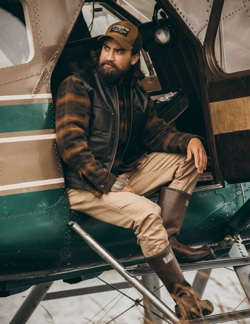 Man sitting on the step of a bush plane wearing Filson Bremerton Work Pants