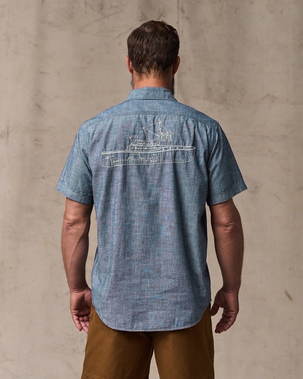 image of a model wearing Filson's Short-sleeve Embroidered Chambray Shirt - Rinsed Indigo