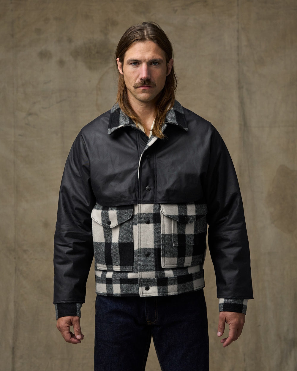 image of a model wearing Filson's Mackinaw Wool Caped Jacket - Natural Black Plaid Navy
